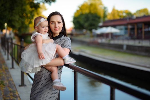 Happy mother and daughter in the park. Beauty nature scene with family outdoor lifestyle. Happy family resting together on the green grass, having fun outdoor. Happiness and harmony in family life.