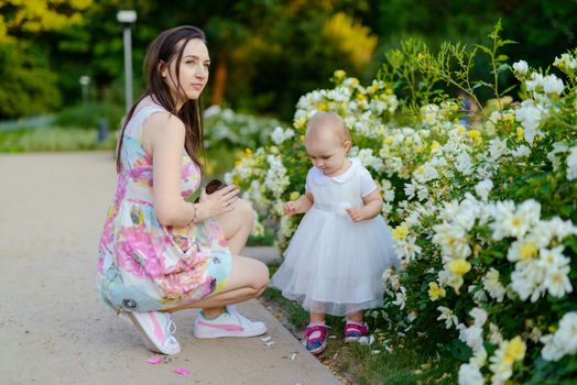 Happy mother and daughter in the park. Beauty nature scene with family outdoor lifestyle. Happy family resting together on the green grass, having fun outdoor. Happiness and harmony in family life.