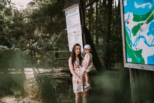 Happy mother and daughter in the park. Beauty nature scene with family outdoor lifestyle. Happy family resting together on the green grass, having fun outdoor. Happiness and harmony in family life.