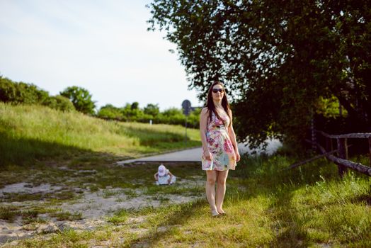 Happy mother and daughter in the park. Beauty nature scene with family outdoor lifestyle. Happy family resting together on the green grass, having fun outdoor. Happiness and harmony in family life.