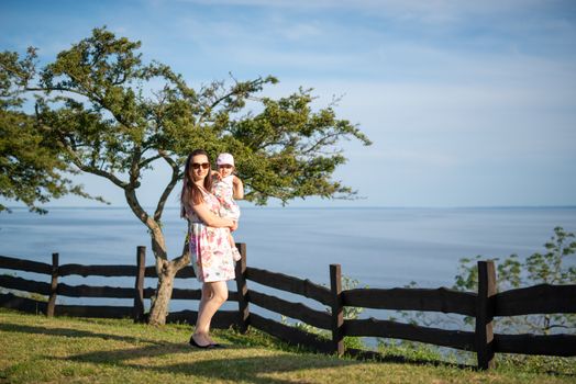 Happy mother and daughter in the park. Beauty nature scene with family outdoor lifestyle. Happy family resting together on the green grass, having fun outdoor. Happiness and harmony in family life.