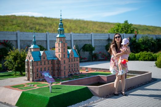 Happy mother and daughter in the park. Beauty nature scene with family outdoor lifestyle. Happy family resting together on the green grass, having fun outdoor. Happiness and harmony in family life.