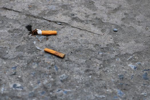 A cigarette used and trash on the concrete floor background,Cigarette that has been exhausted,Smoking Incorrect
