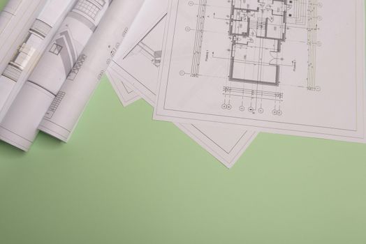 White family paper house , stack of money coins, house projects plan and blueprints on mint background paper. Minimalistic and simple concept, style. Vertical orientation