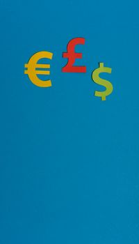Paper yellow symbols of euro, dollar and pound currency on blue background. View from above with copy space