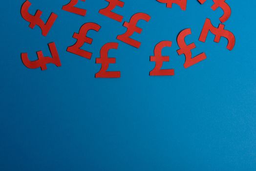 Paper yellow symbols of british pound currency on blue background. View from above with copy space