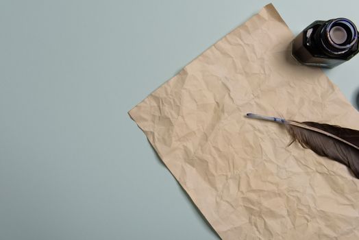 Raven feather, inkwell and old yellowed paper on red background. Copy space. Old letter.