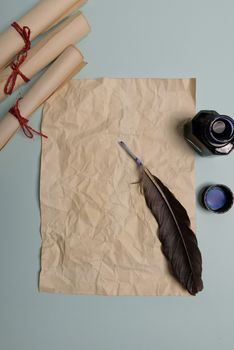 Raven feather, inkwell and old yellowed paper on red background. Copy space. Old letter.
