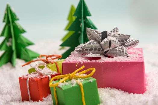 christmas presents nicely decorated with bows and feathers in snow. view from above