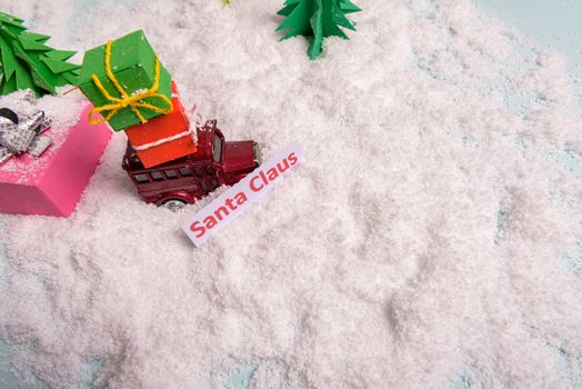 a toy car carries presents under the Christmas tree at snow. view from above. copy space