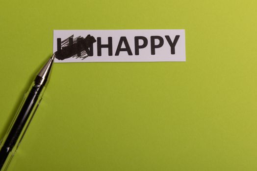 card with text unhappy, cutting word 'un' so it written 'happy'. Copy space. Lime background. Studio shoot.