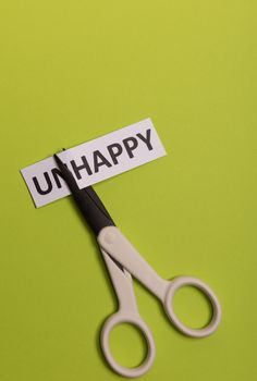 card with text unhappy, cutting word 'un' so it written 'happy'. Copy space. Lime background. Studio shoot.