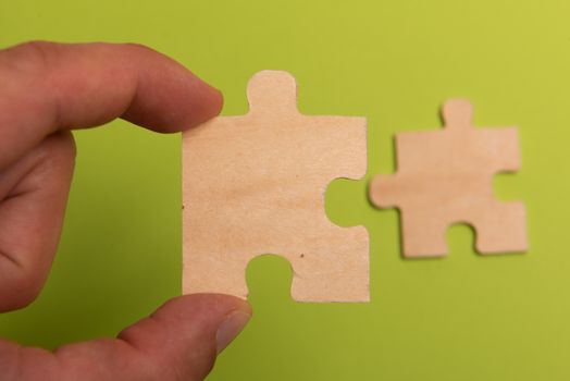 Man hand assembling puzzles on lime background.