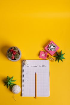 gift box and green origami trees with notepad on yellow desk, table