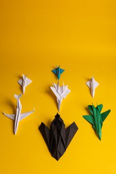 Group of paper plane in one direction and with one individual pointing in the different way on yellow background. Smoke coming out from aircraft tails