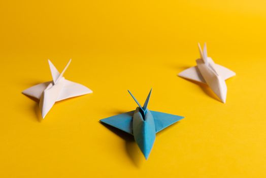 Group of paper plane in one direction and with one individual pointing in the different way on yellow background. Smoke coming out from aircraft tails