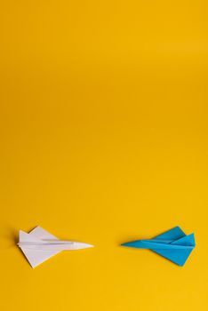 Group of paper plane in one direction and with one individual pointing in the different way on yellow background. Smoke coming out from aircraft tails