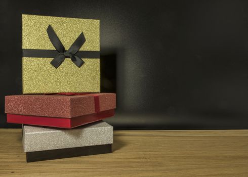 three gift boxes in red silver and gold on black background