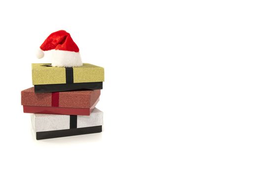 three gift boxes in red silver and gold with santa claus hat isolated on white background