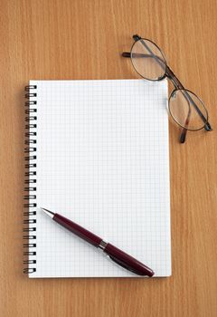 Notebook, glasses and pen on the table.