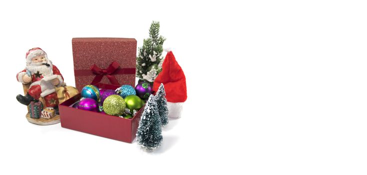 santa claus and a box with christmas balls with christmas trees as decoration on white isolated background