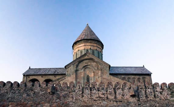old church with a stone wall in Georgia against a blue sky