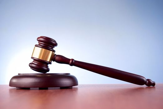 brown gavel with a brass band on a blue background