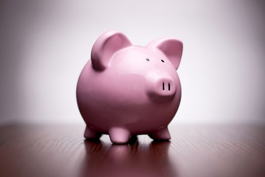 Small ceramic pink piggy bank with vignetting, conceptual of money, finances, retirement and saving for your dreams and goals