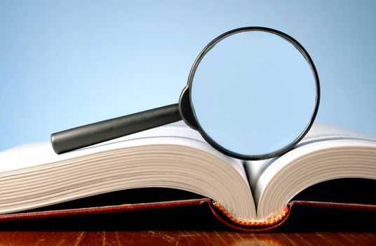 magnifying glass and an open book on a table
