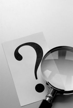 magnifying glass and a question mark on the paper