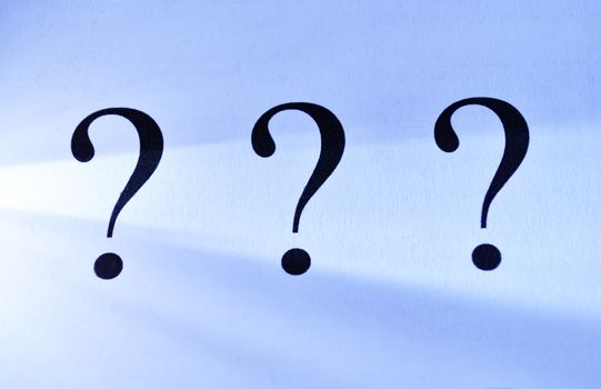 Three question marks on an abstract blue background depicting unanswered questions, interrogation, confusion and solutions