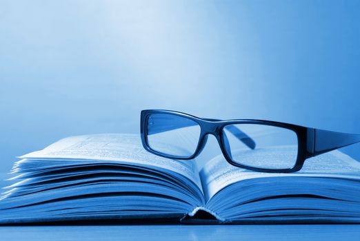 black-rimmed glasses and a book on the table