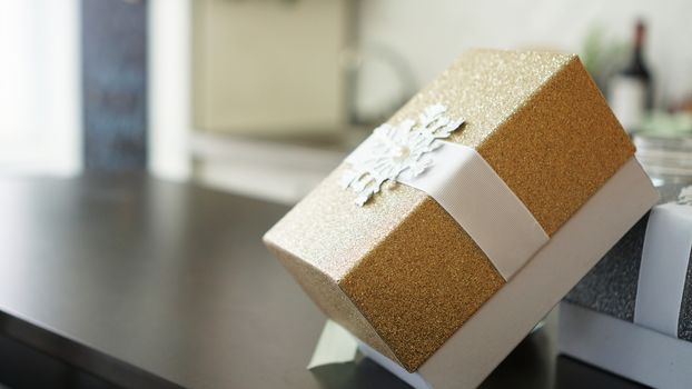 Gold present box on wood table with blurred background with place for text, Holiday concept