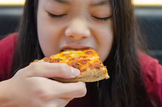 Asian Child girl with long hair eat pizza.