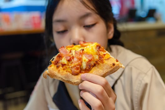 Beautiful Asian girl eating pizza in the restaurant.