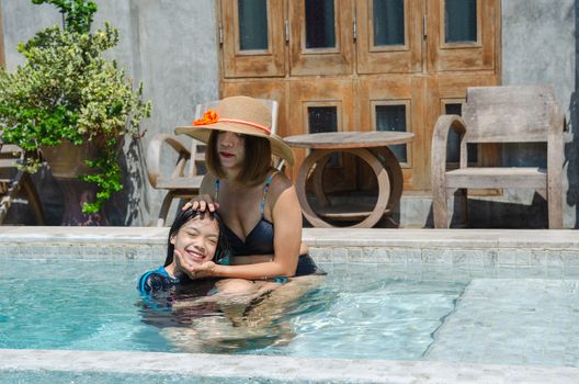 Asian mother and daughter family playing in the pool