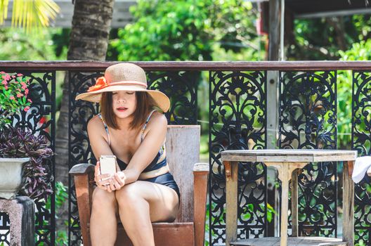 Portrait of sexy Asian  woman wearing a  swimsuit play smartphone.