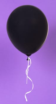Black balloon isolated on a purple background