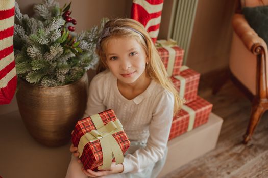 Teen girl with present near Christmas tree