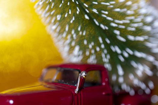 Toy car carries Christmas tree for holiday.