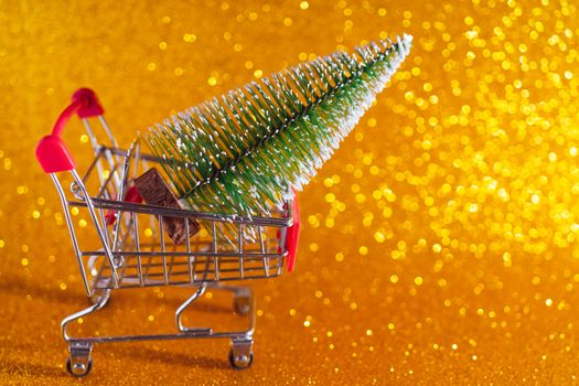 Christmas golden background. Supermarket cart and Christmas tree.