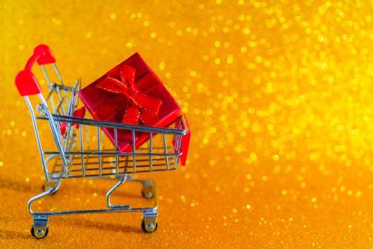 Christmas golden background. Christmas present in a supermarket trolley.
