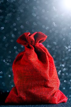 Christmas shiny black background. Red gift bag.  Beautiful bokeh.