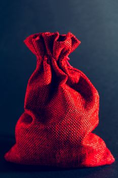 Red bag of Christmas gifts on a black background.