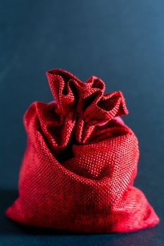 Red bag of Christmas gifts on a black background.