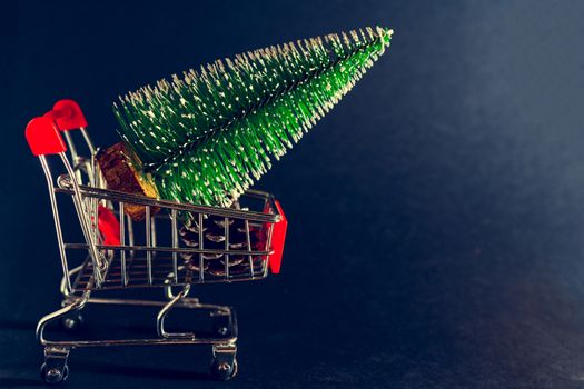 Christmas black background. Supermarket trolley and Christmas tree.