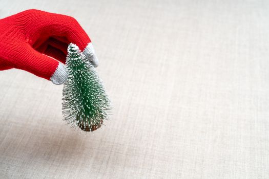 female hand in a red glove lays a Christmas tree on a table.