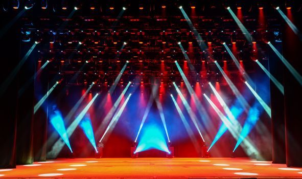 Illuminated empty show stage with scenic fog and red, white and blue light beams