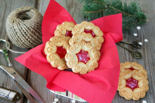 Biscuit Christmas cookies with red jam in the tin box on an old wooden table