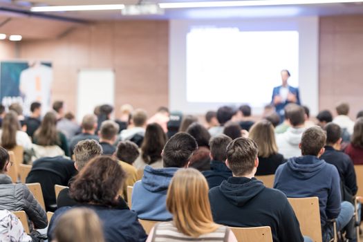 Speaker giving a talk in conference hall at business event. Audience at the conference hall. Business and Entrepreneurship concept. Focus on unrecognizable people in audience.